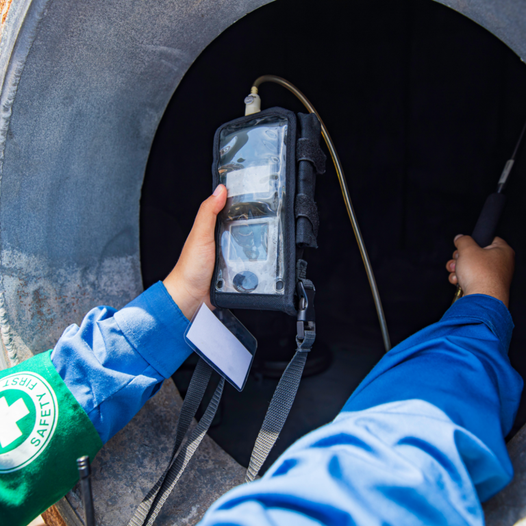 Persona sosteniendo un dispositivo electrónico mientras trabaja en un entorno industrial.