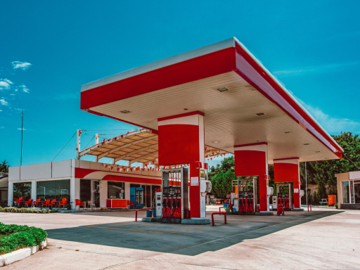 Estación de servicio moderna con estructura roja y blanca bajo un cielo azul.