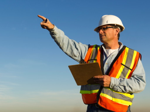Trabajador de la construcción con casco y chaleco, señalando hacia el horizonte.